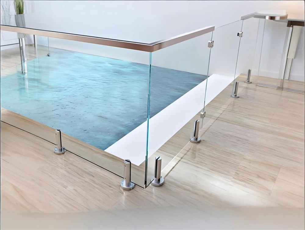 Glass railing beside a swimming pool with stainless steel top rail